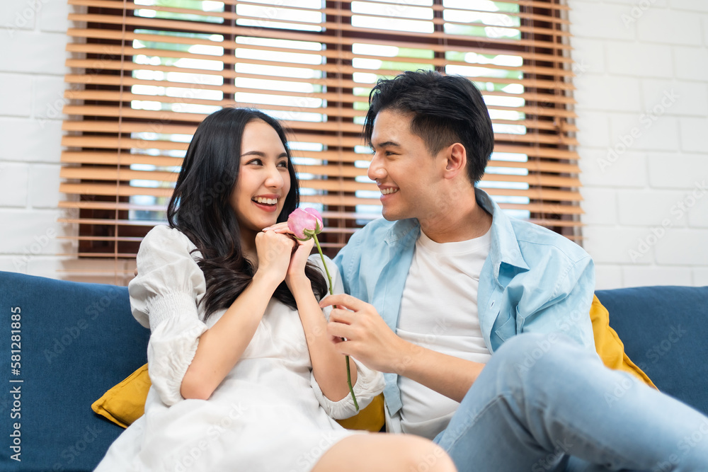 Asian young man surprise and give rose flower to beautiful girlfriend. 