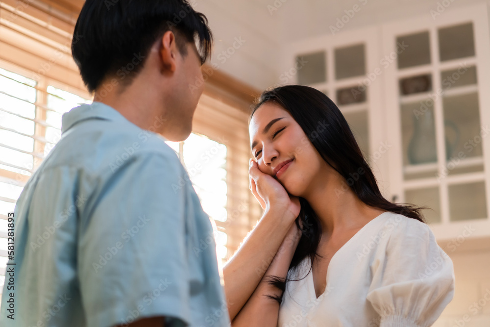 Asian young man and woman looking each other in living room at home. 