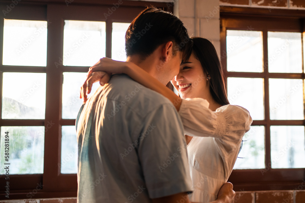 Asian young man and woman hugging each other in living room at home. 