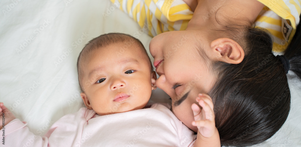 Loving Asian Mom carying of her newborn baby at home in the bedroom. happy family. mother playing wi