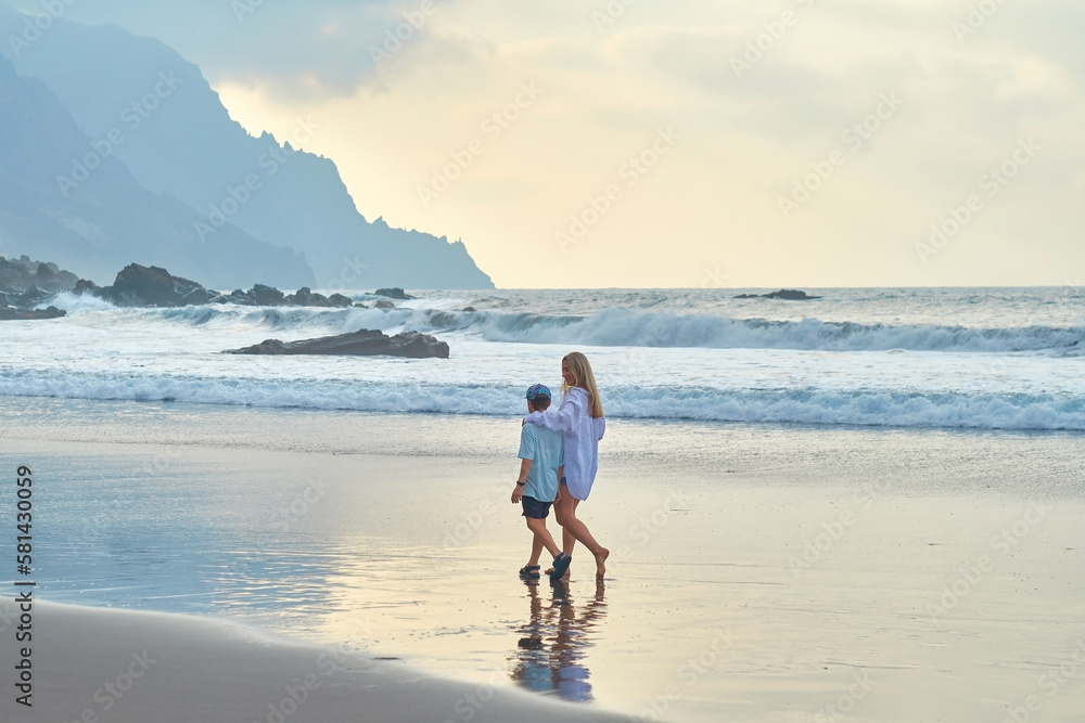 Happy Family, mother and son walking, playing, laughing on the beach. Mother hugging child. Enjoying