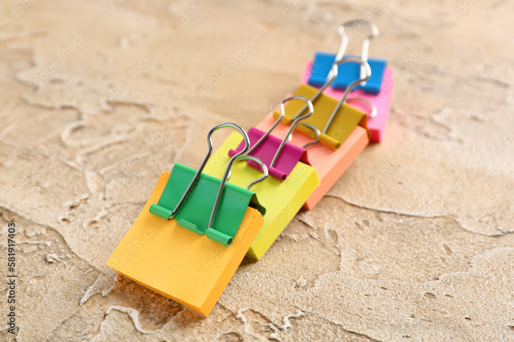 Sticky notes with colorful binder clips on color background