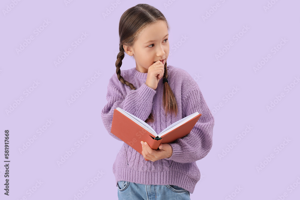 Little girl with book biting nails on lilac background