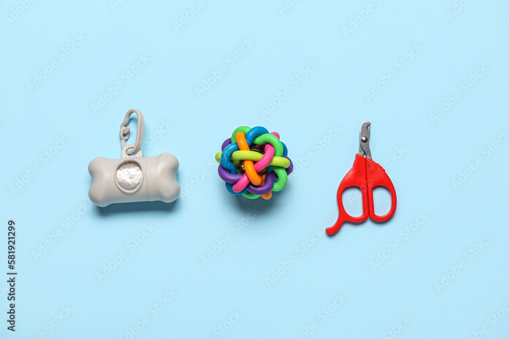 Nail clipper, toy and waste bags on color background