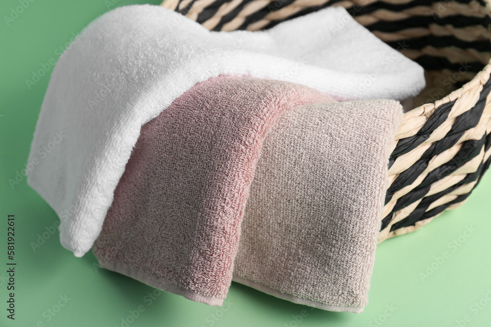 Basket with folded soft towels on green background