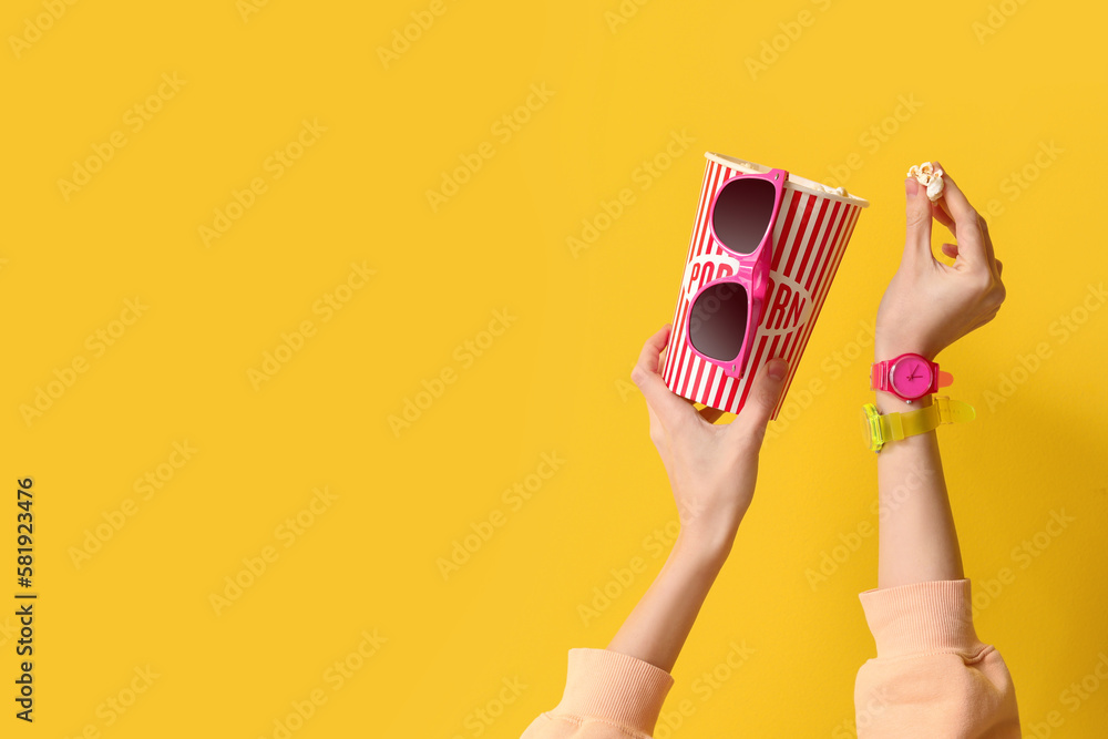 Woman with wristwatches, popcorn and 3D glasses on yellow background