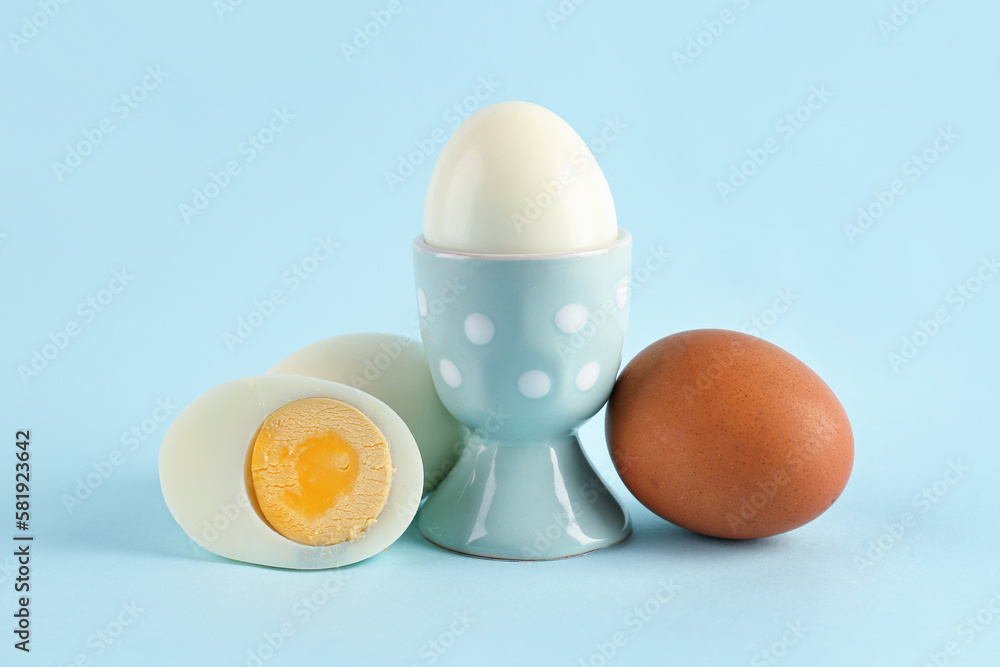 Holder with delicious boiled egg on blue background