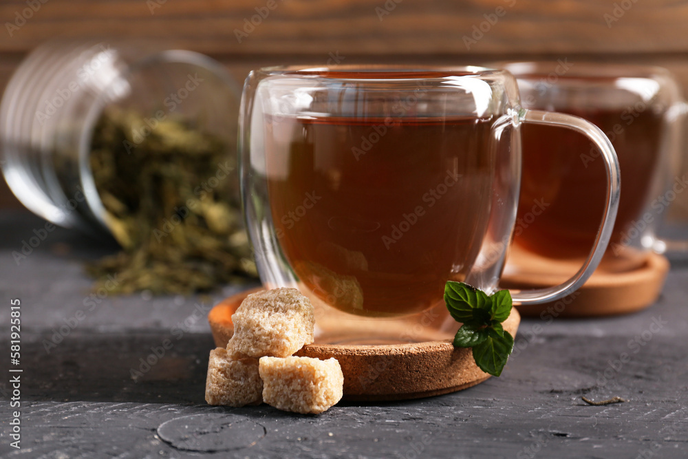 Glass cups of tasty green tea and cane sugar on dark wooden background, closeup