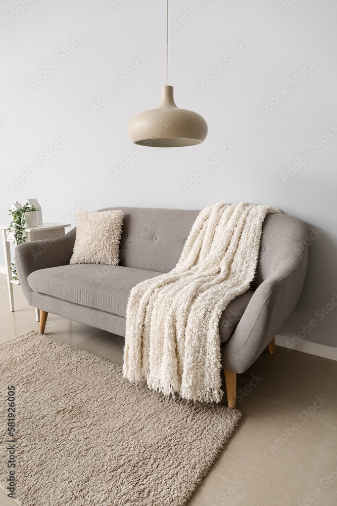 Interior of light living room with grey couch, table and lamp