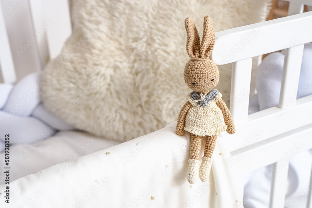 Toy bunny on baby crib in bedroom, closeup