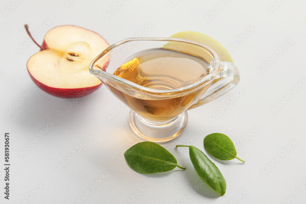 Gravy boat with fresh apple cider vinegar and fruits on grey background