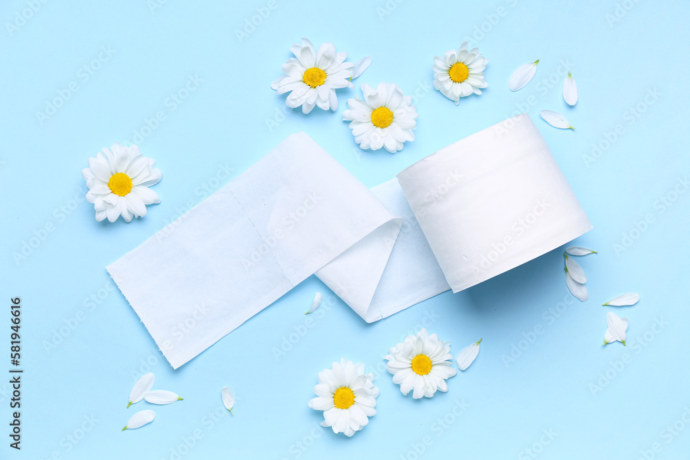 Composition with roll of paper and beautiful chamomile flowers on color background