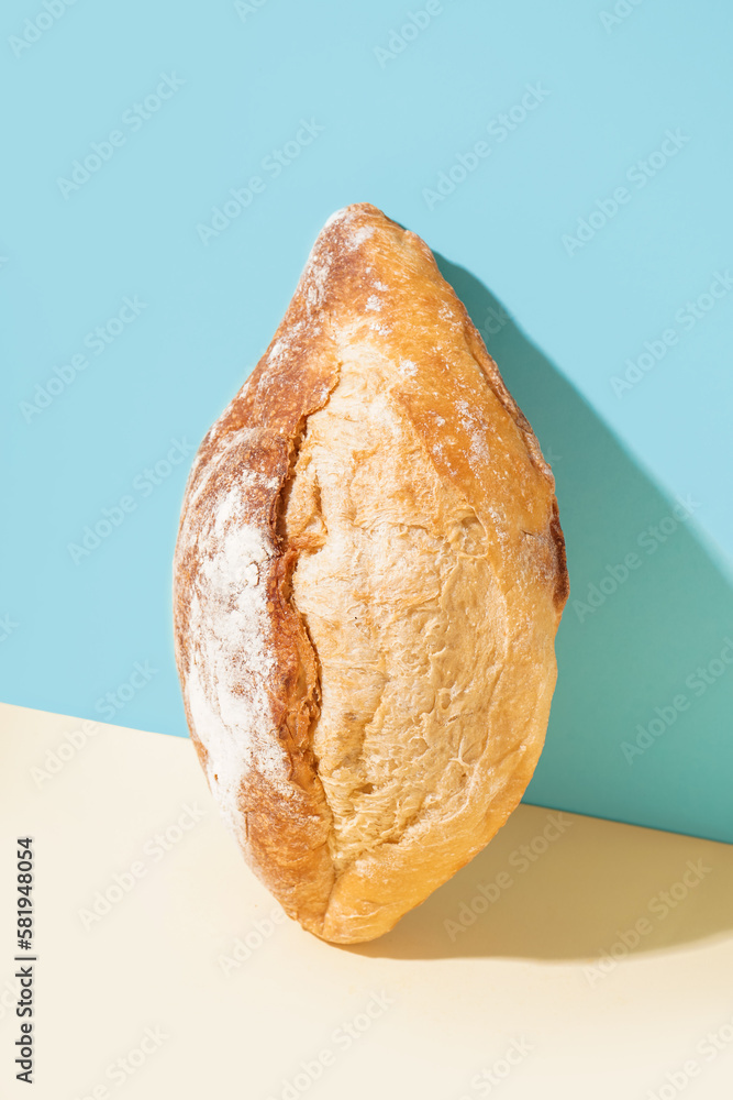 Loaf of fresh bread on beige table near blue wall