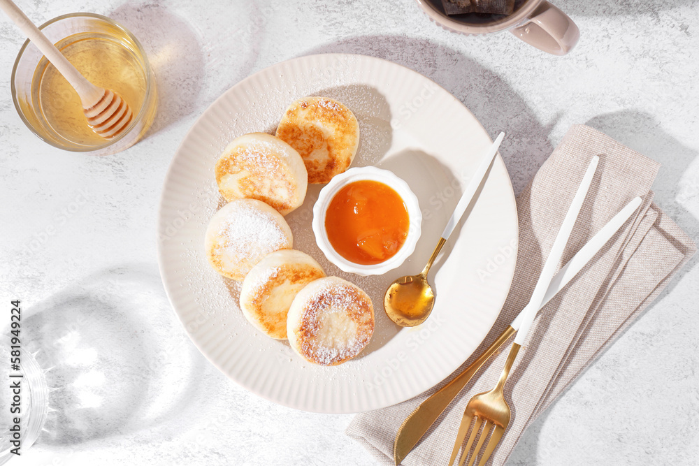 Plate with tasty cottage cheese pancakes, jam and honey on light background