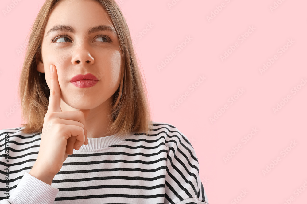 thoughtful young woman in striped sweatshirt on pink background, closeup