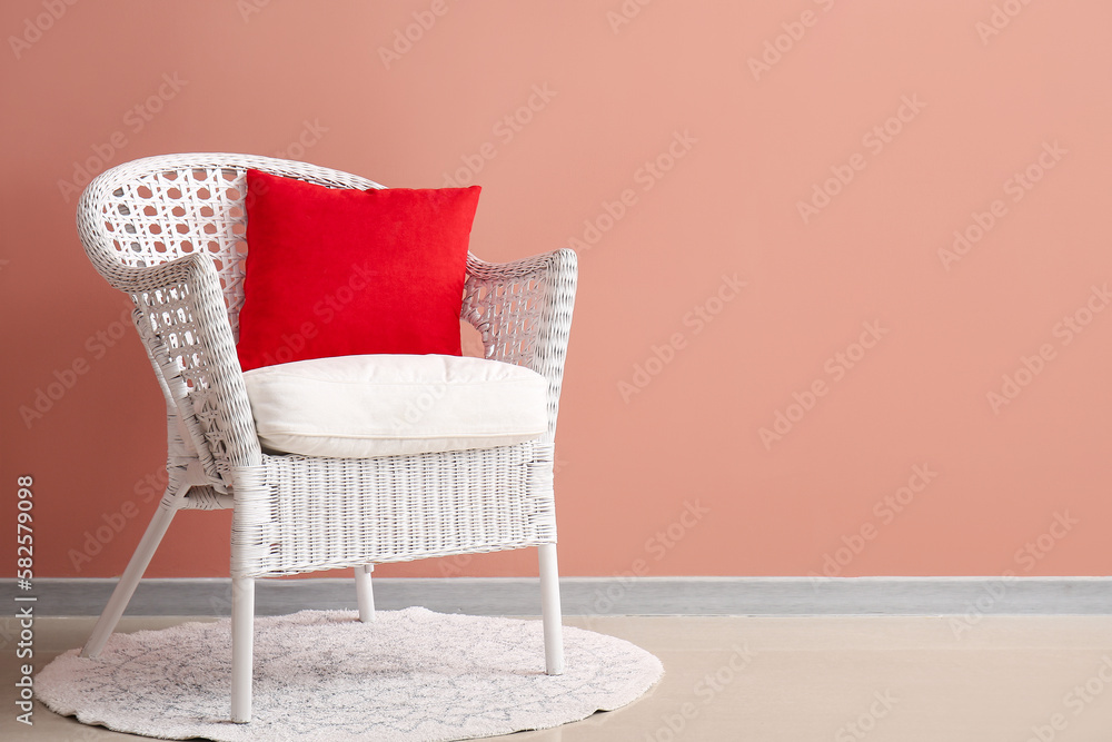 Stylish decorative pillows on cozy armchair near pink wall