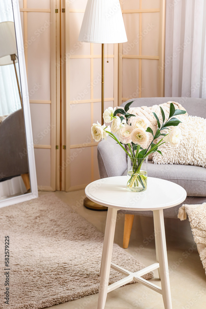 Vase with ranunculus flowers on table in interior of living room