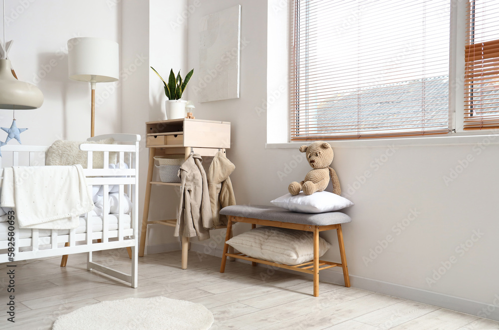 Interior of light childrens bedroom with baby crib, table and bench