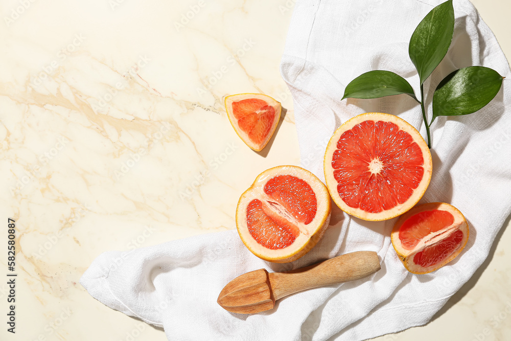 Composition with cut ripe grapefruits, juicer and plant branch on light background