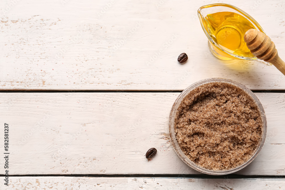 Jar of body scrub and honey on light wooden background