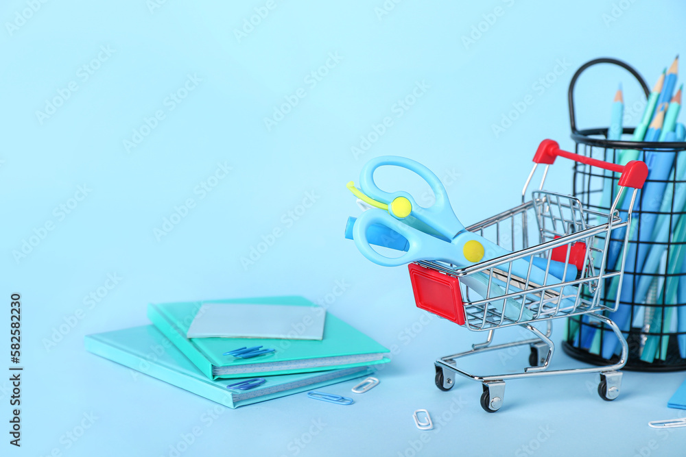 Shopping cart with stationery on blue background