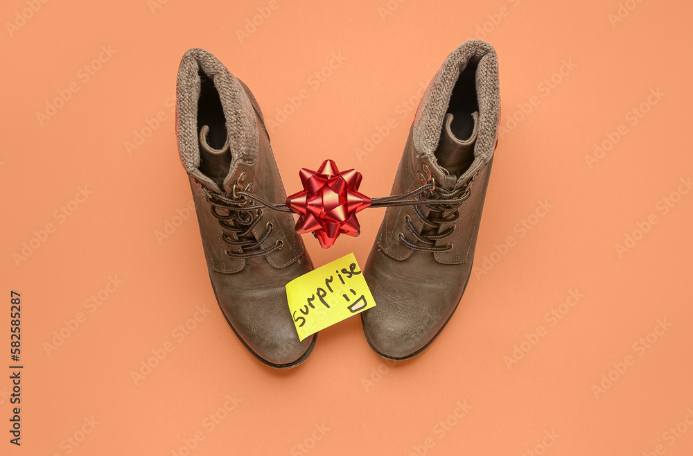 Paper with word SURPRISE, boots and bow on red background. April Fools Day celebration