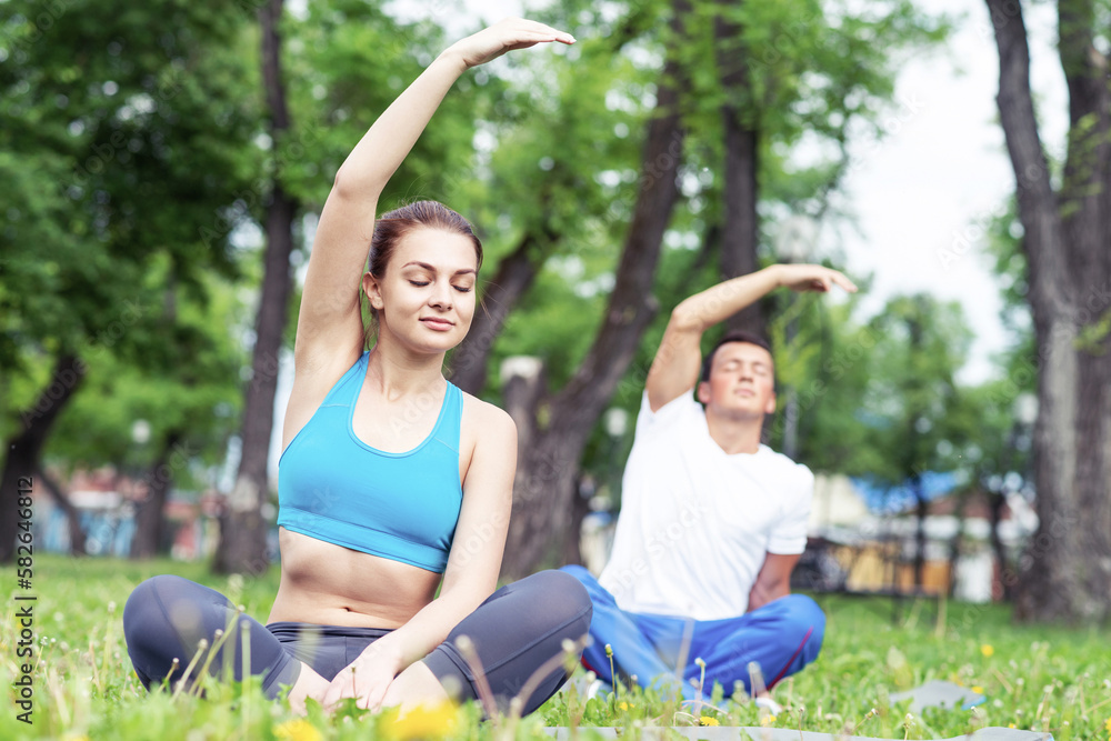 Young couple doing yoga in park together