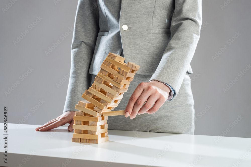 Businesswoman removing wooden block from tower