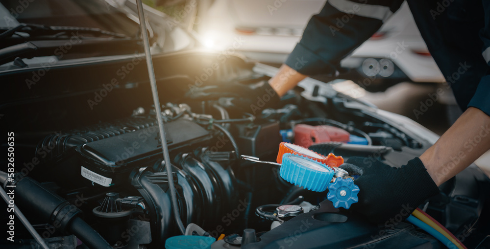 Close up hand of auto mechanic using measuring manifold gauge check the refrigerant and filling car 