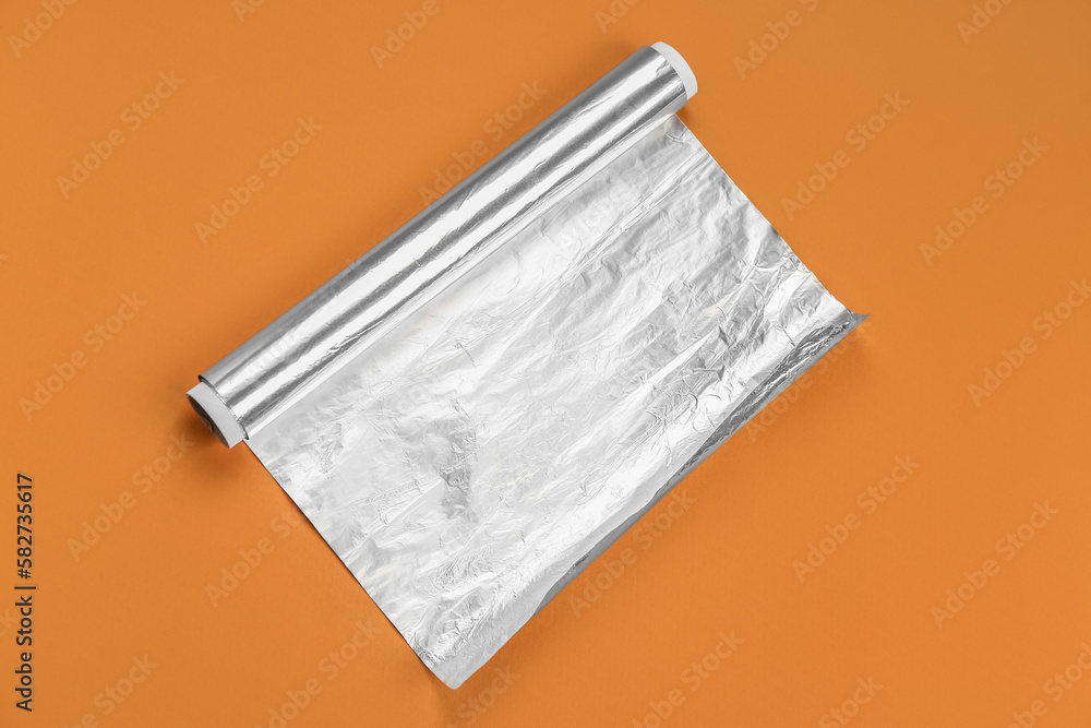 Aluminium foil roll on orange background