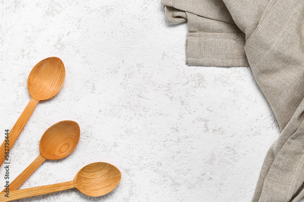 Wooden spoons and napkin on light background