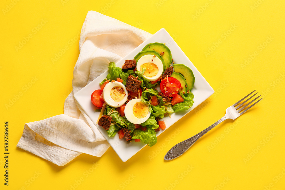 Plate of delicious salad with boiled eggs and salmon on yellow background