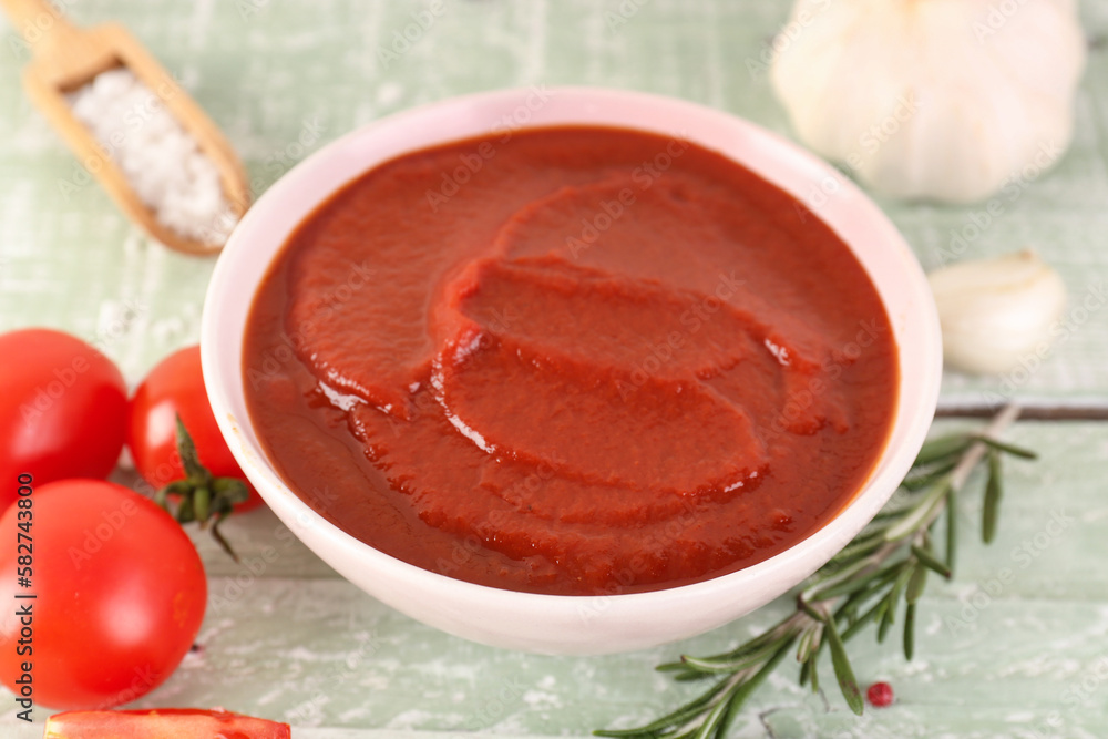 Bowl of tasty tomato paste on green wooden background