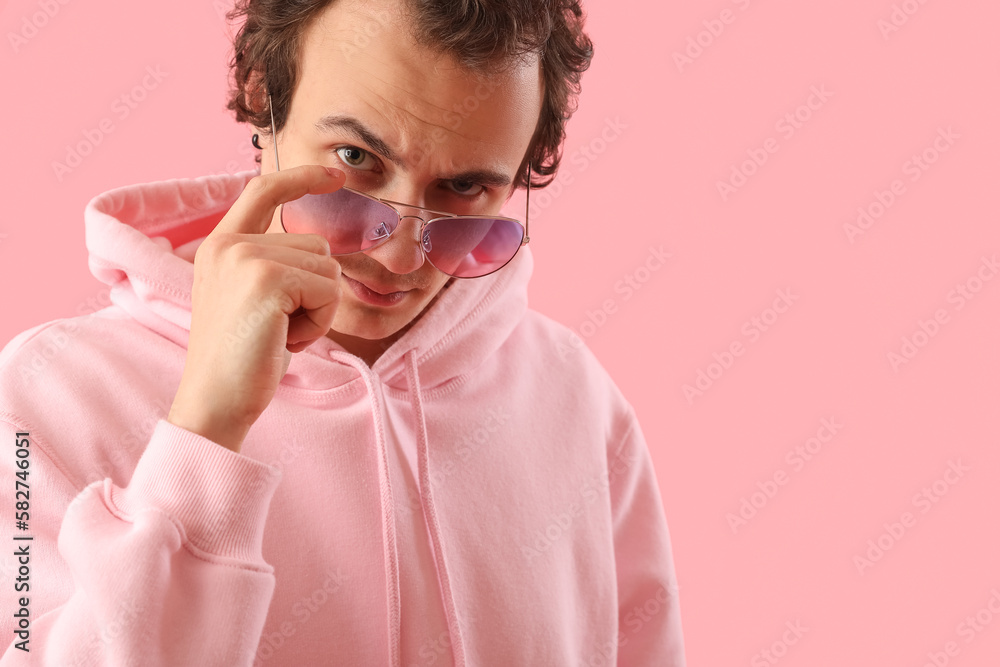 Young man in sunglasses on pink background, closeup