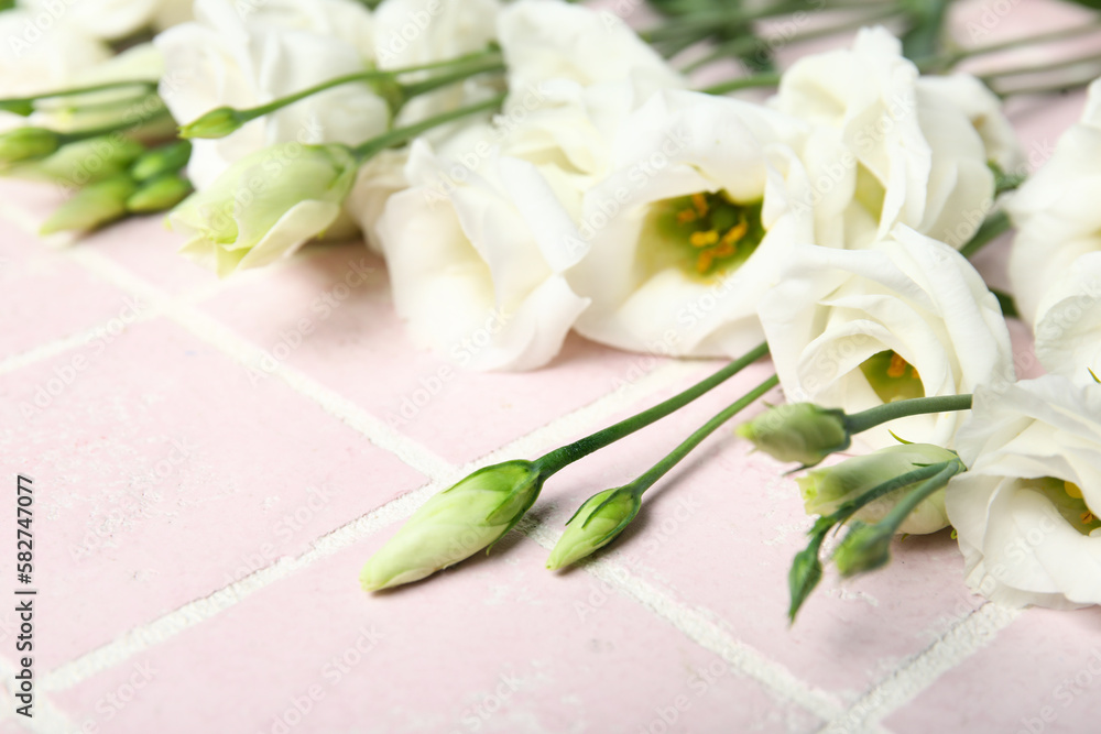 White eustoma flowers on color tile background, closeup