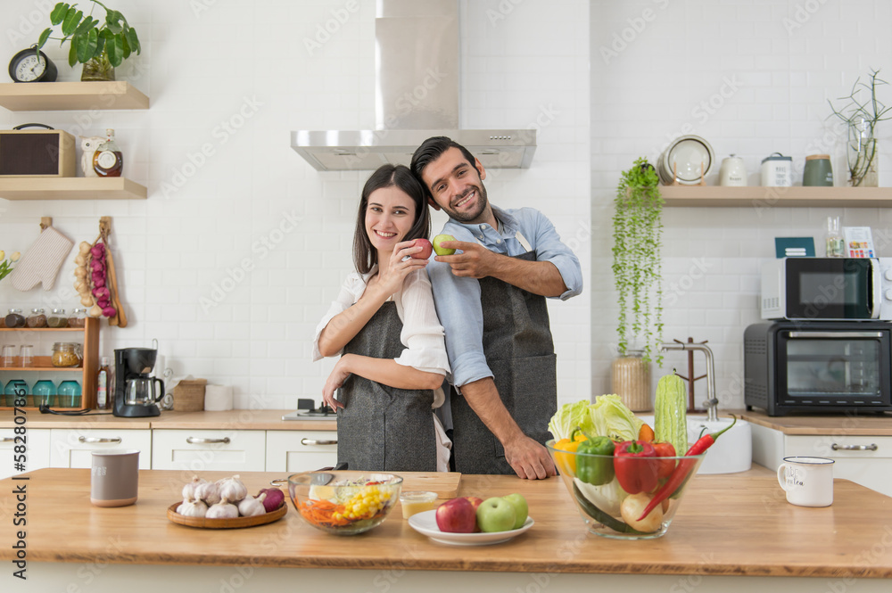 Happy young couple cooking together in the kitchen at home