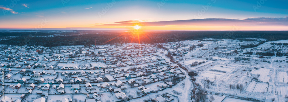 Sunny Winter Day. Aerial Panoramic View Of Small Town Village Cityscape Skyline Traffic In Snowy Lan