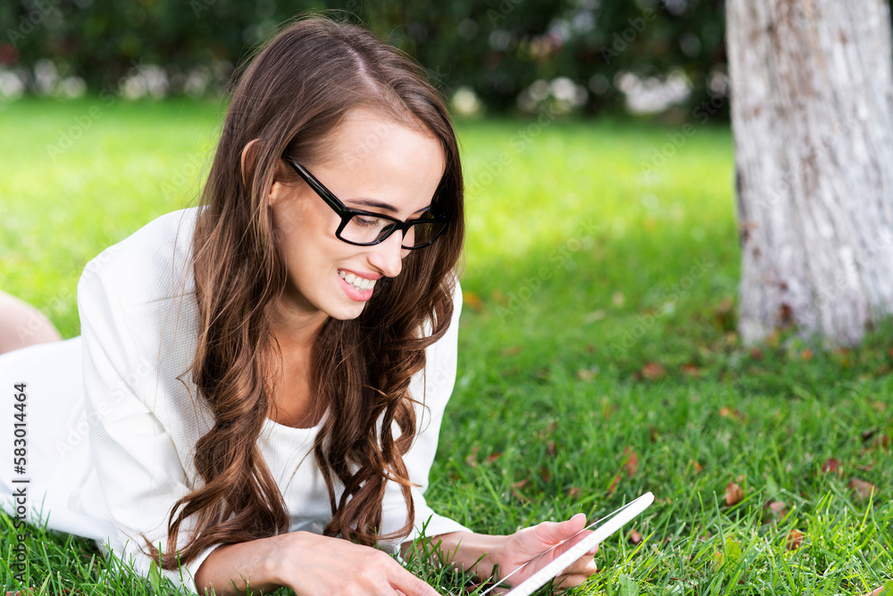 Young woman with digital tablet laying on grass