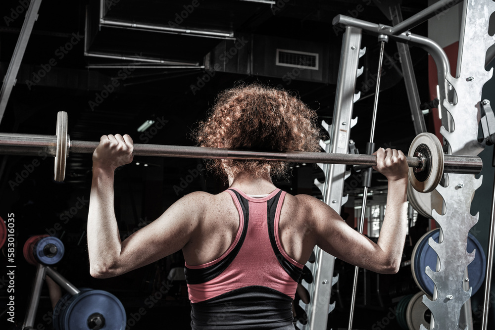 Woman bodybuilder engaged with a barbell in the gym