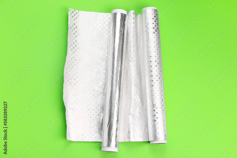 Rolls of aluminium foil on green background