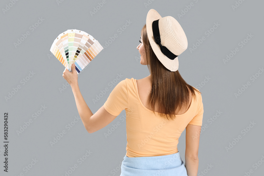 Beautiful woman with paint color palettes on grey background