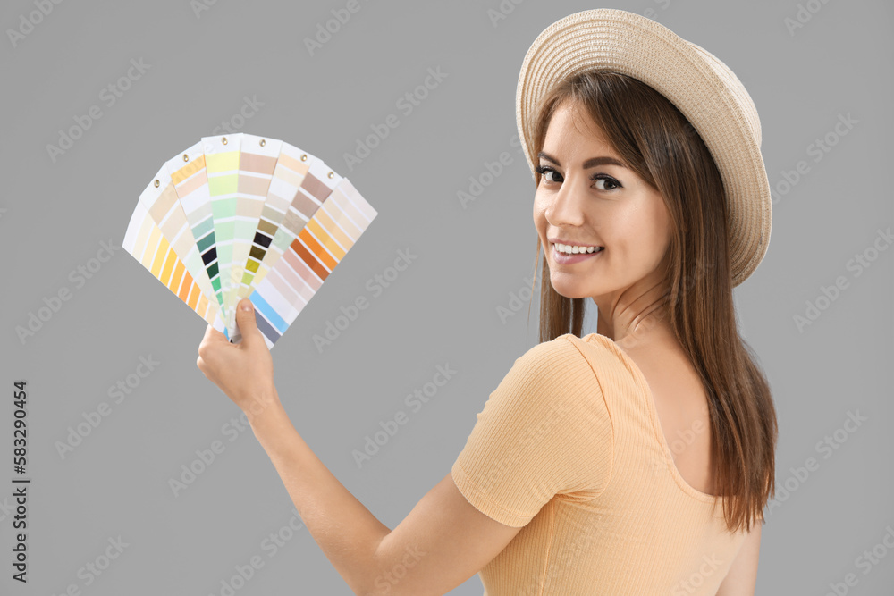 Beautiful woman with paint color palettes on grey background