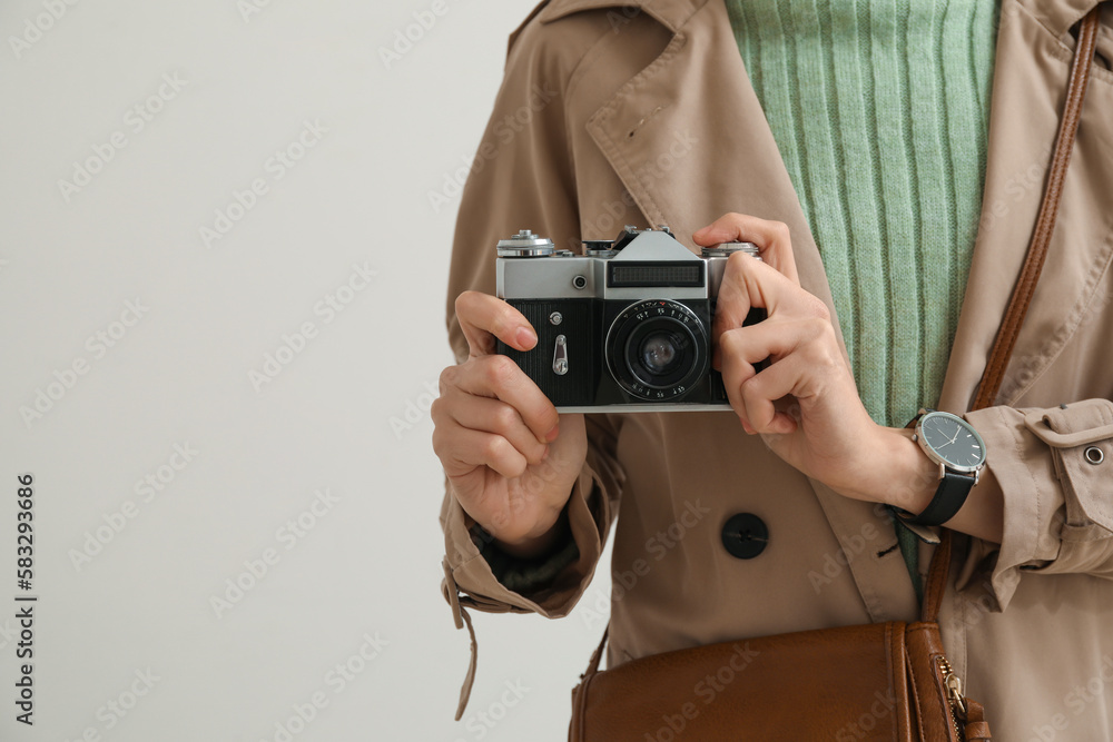 Woman with wristwatch and photo camera on light background, closeup