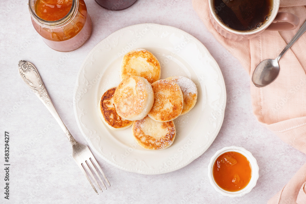 Plate with tasty cottage cheese pancakes and jam on light table