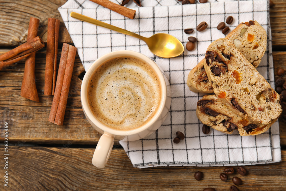 Delicious biscotti cookies, cinnamon, beans and cup of coffee on wooden background