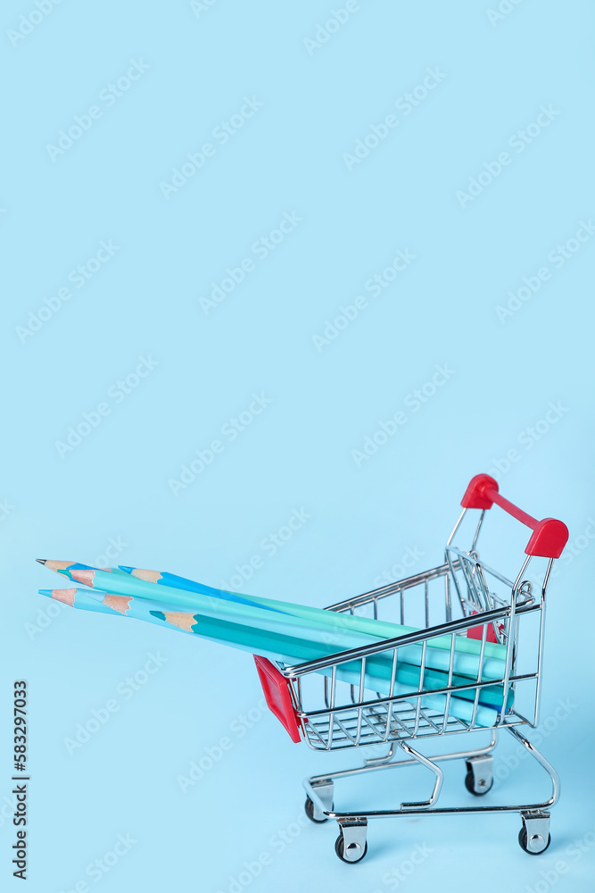 Shopping cart with pencils on blue background