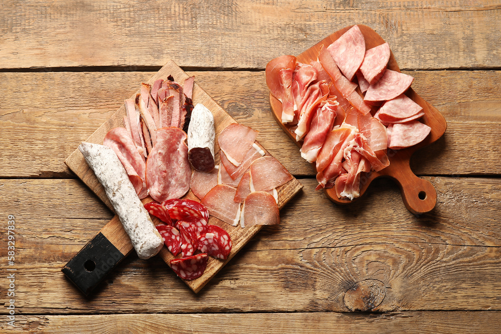 Boards with assortment of tasty deli meats on wooden background