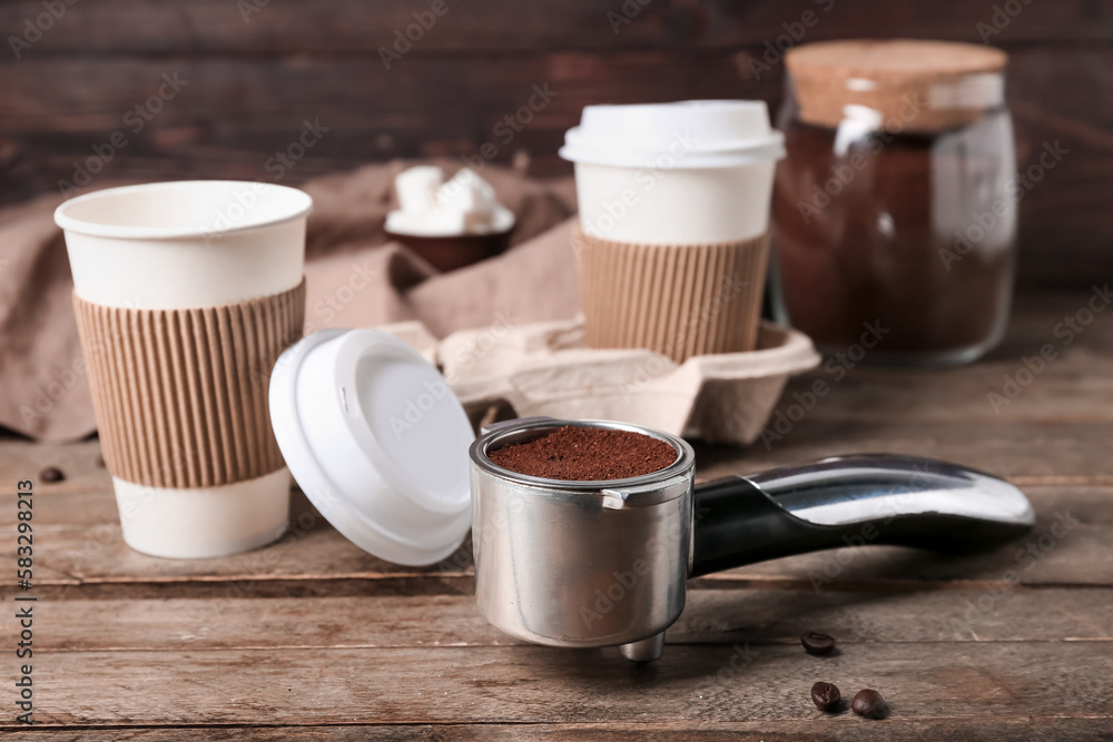 Scoop of coffee powder and cups on wooden table, closeup