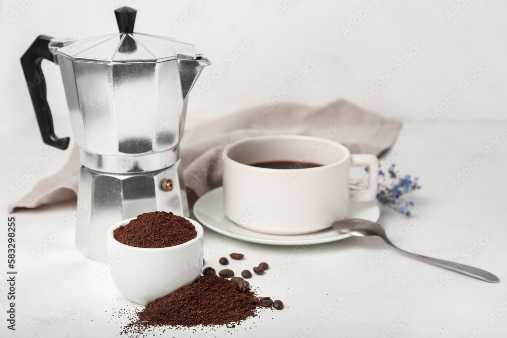 Bowl of coffee powder, cup and maker on white table