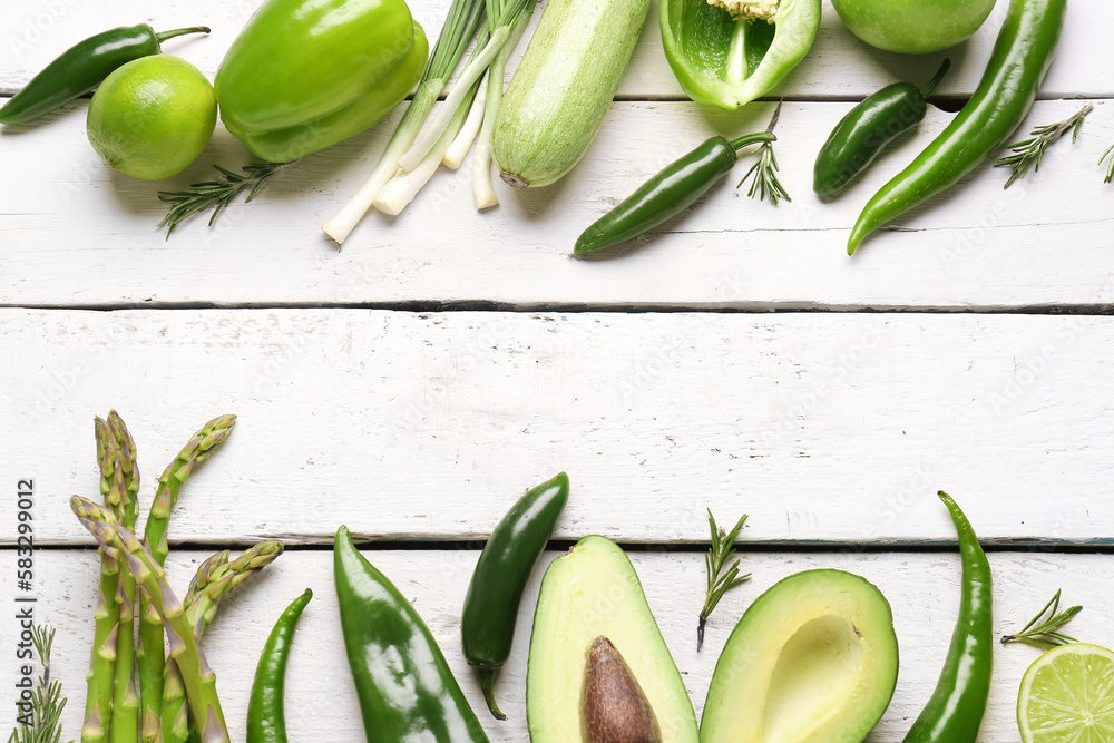 Frame made of different green vegetables on white wooden background